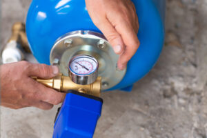 Blue water pressure tank with a pressure gauge. Benefits of a water pressure tank - JB Water Well.