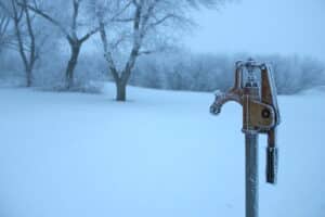 A frosty rural water pump on a farm against a wintry backdrop. A frosty rural water pump on a farm against a wintry backdrop.